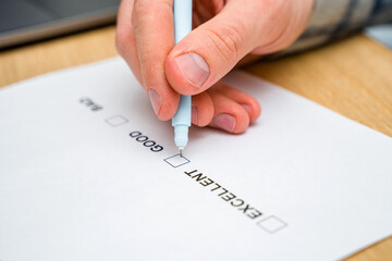 A questionnaire with answer options for the feedback form. A man ticks a box on a white paper while...