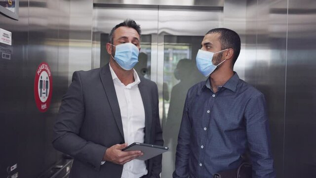 Two businessmen in the elevator wearing face mask due to Covid