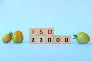 ISO 22000 or Food Safety Management System on wooden blocks in blue background.