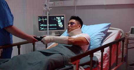 Injured male patient lying in hospital bed and paying with credit card for treatment