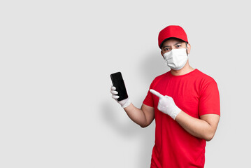 Delivery man employee in red cap blank t-shirt uniform face mask hold black mobile phone application isolated on white background