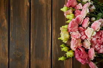 pink eustoma and rose flowers on wooden surface