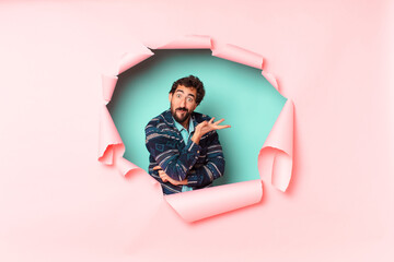 young crazy bearded man. confused or doubting expression. paper hole empty background concept