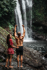 Couple at the waterfall, rear view. Honeymoon trip. Couple on vacation in Bali. A couple in love travels the world. Vacation on the island of Bali. Happy couple close up. Tourists at the waterfall