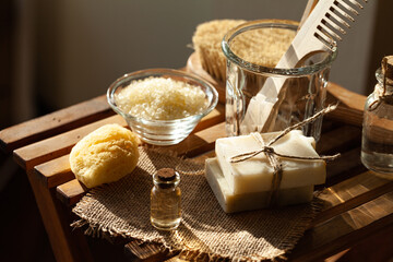 Zero waste and sustainable lifestyle concept. Eco-friendly bathroom accessories. Handmade soap, organic essential oil, sea salt, wooden background. Home body and face care. Contrast light, close-up