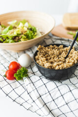 Cooked quinoa porridge is on the table along with salad. Cooking process in the kitchen. Kitchen utensils and ambiance.