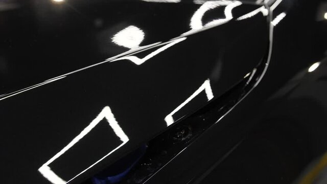 Black car hood after polishing. Close up view of hood car. Process of polishing auto.