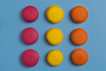 Red yellow and orange macarons on a blue background