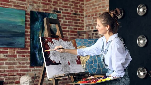 Young beautiful female artist painting still life with sunflower on canvas using oil paintings and art brush. Painter creating artwork in art studio. Relaxation, leisure, hobby, stress management.