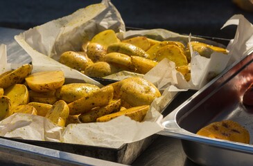 Street food in Ukraine - grilled  potatoes lying on a metal tray tray in parchment paper and ready to be served