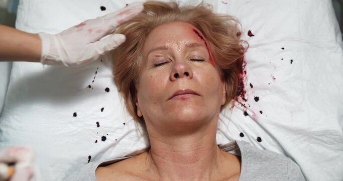 Top view of medic with flashlight checking condition of unconscious bleeding woman