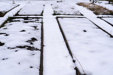 Home garden beds are covered with snow in spring, unexpected snow for gardeners