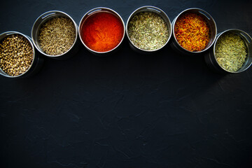large set of Indian spices and herbs. On a black board.