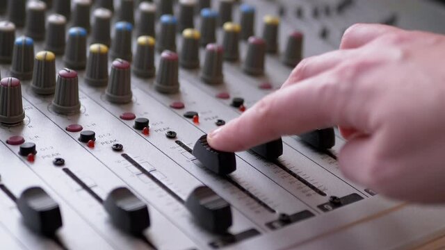 Sound Engineer, DJ Moves Sliders with Fingers on Audio Mixer in Recording Studio