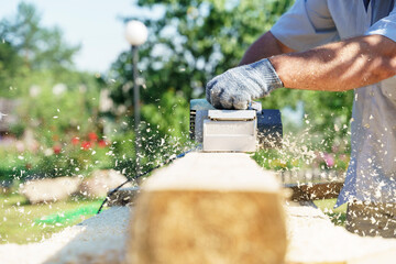 a carpenter works with an electric pipe on a sunny day