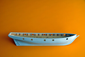 Making a model of a sailing ship, the hull of the ship on a yellow background.