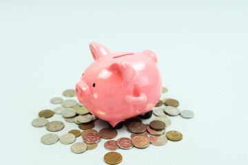 piggy bank business standing on a pile of coins concept. A hand is putting a coin in a lifestyle piggy bank on a yellow background. saving money is an investment for the future. Banking investment