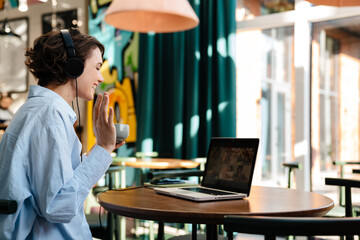 Back view of a happy attractive young woman in headphones