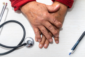 Hand of elderly man with osteoarthritis at doctor's office on white table