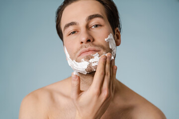 Attractive young smiling nude man with shaving foam