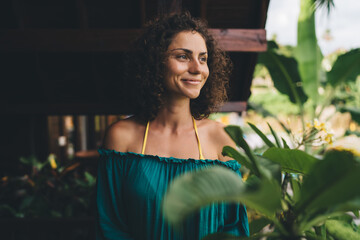 Smiling woman standing outdoors near green plant