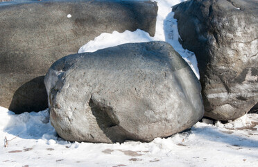 Large stones in the snow. View of the stones boulders lying on the snow.