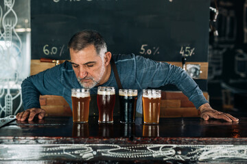 barman smelling fresh beer in glasses