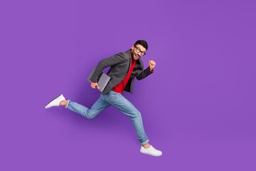 Fototapeta na wymiar Full size profile photo of optimistic nice brown hair man jump with laptop wear spectacles sweater isolated on purple background