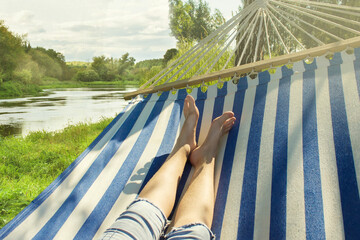 feet of young girl on hammock. resting on the background of river. summer concept
