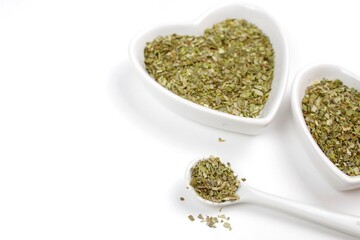 Dried herbs or spices in a bowl with spoon on a white background 