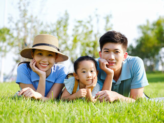 Fototapeta premium Happy family of three lying on the grass