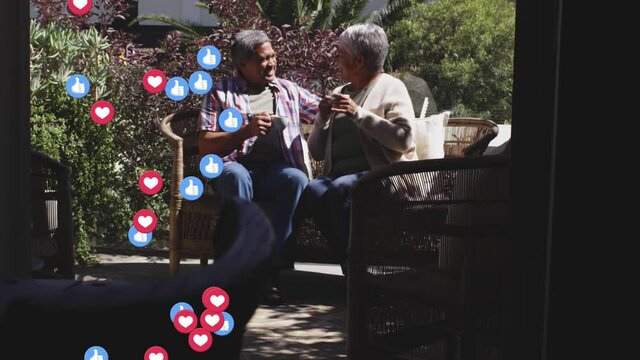 Multiple heart and thumbs up icons floating against african american couple drinking coffee together