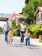 Happy family of four flying kites outdoors