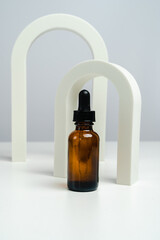 Massage oils in a dark glass jar. Essence for skin health against the backdrop of arches. Trendy style. Geometric figures. Photo in monochrome style. Mockup for your product. Conceptual photo. 