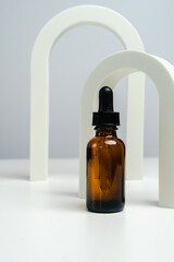 Massage oils in a dark glass jar. Essence for skin health against the backdrop of arches. Trendy style. Geometric figures. Photo in monochrome style. Mockup for your product. Conceptual photo. 