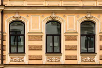 Detail of yellow cream art nouveau building facade of three windows reflecting facade opposite of street in Riga, Latvia, Europe