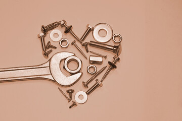 wrench repairs a heart made of nuts bolts screws and self tapping screws on a light pastel background
