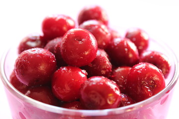 cherry in a glass on a pink red background with a place to text the view from the side close-up of the copyspace