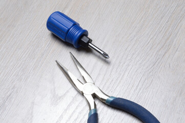 screwdriver tool and pliers lie on a light-colored countertop.