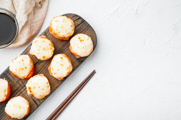 Baked sushi roll with shrimp and masago caviar cap. Traditional sushi restaurant dish, on white stone  background, top view flat lay , with copyspace  and space for text