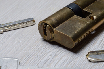 the disassembled door lock and the keys to it lie on a light surface. close-up.