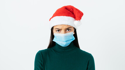Wearing a protective mask for Christmas disgruntled young woman in red Santa hat