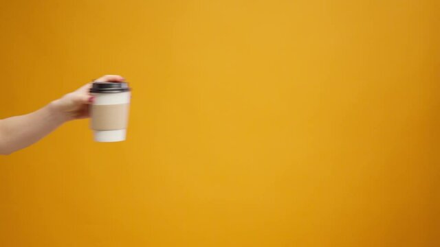 People's hand passing one another coffee to go, coffee delivery against yellow background