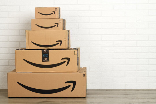 Group of Amazon cardboard boxes on white brick wall background. Bergamo, Italy, 5 march 2021.