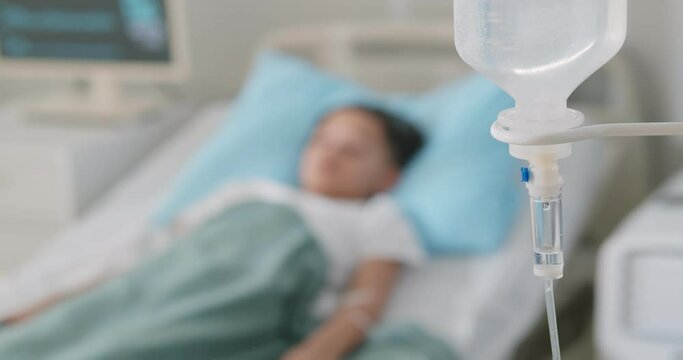 Doctor setting up iv for sick african kid resting in hospital bed