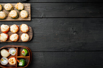 Obraz na płótnie Canvas Japanese sushi rolls named Baked Ebi with wasabi and salmon fish, on black wooden table background, top view flat lay , with copyspace and space for text