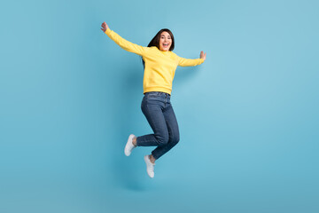 Fototapeta na wymiar Photo of excited crazy lady jump raise hands open mouth wear yellow jumper jeans sneakers isolated blue background