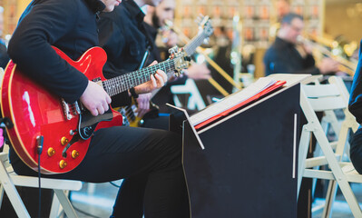 Musician in the orchestra plays the electric guitar.