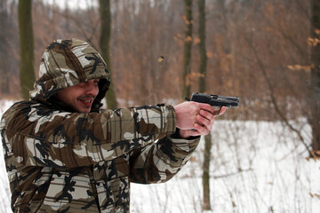 Soldier shooting with a pistol in the forest in winter