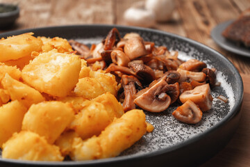 Close-up of fried mushrooms and potatoes on a gray concrete plate